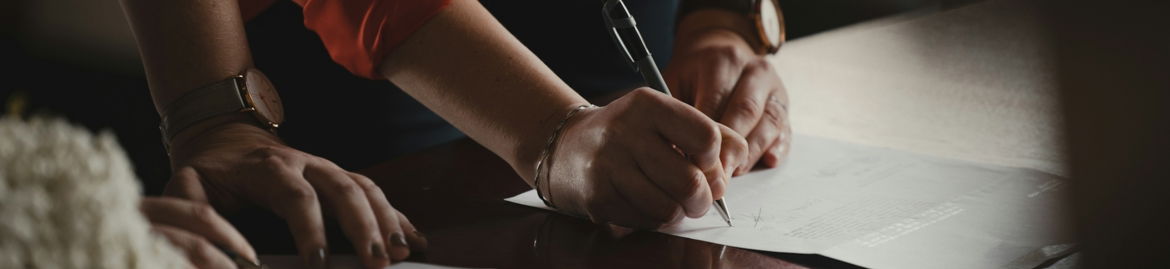 person in orange long sleeve shirt writing on white paper